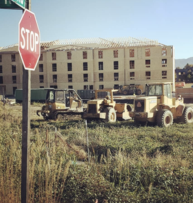 Multi-story multifamily building under construction with equipment on site