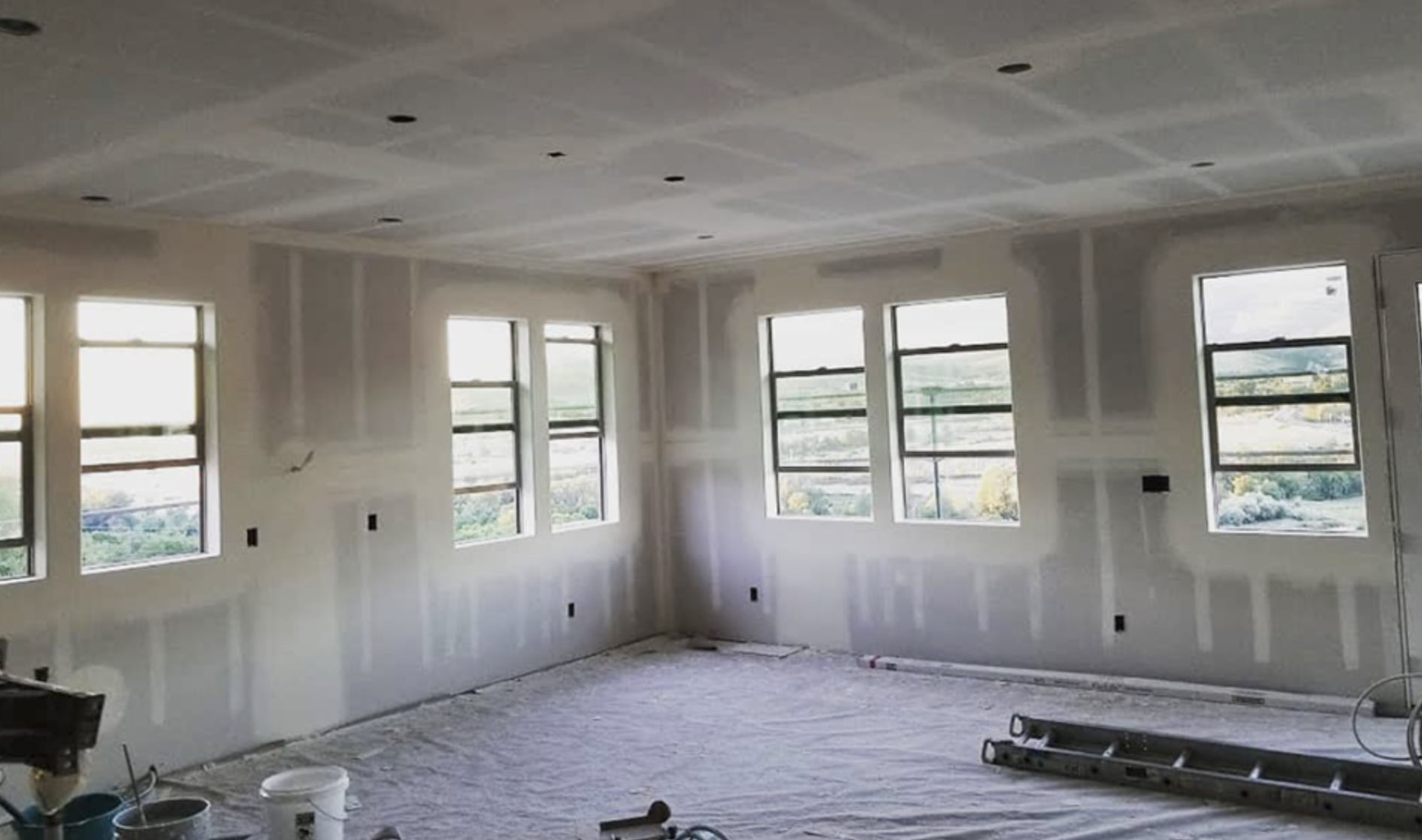 Wide living space with finished ceiling and taped window walls